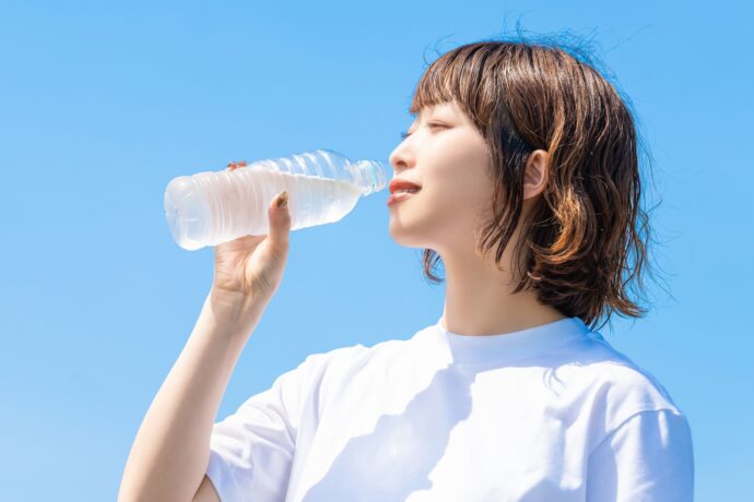 青空の下で水を飲む女性