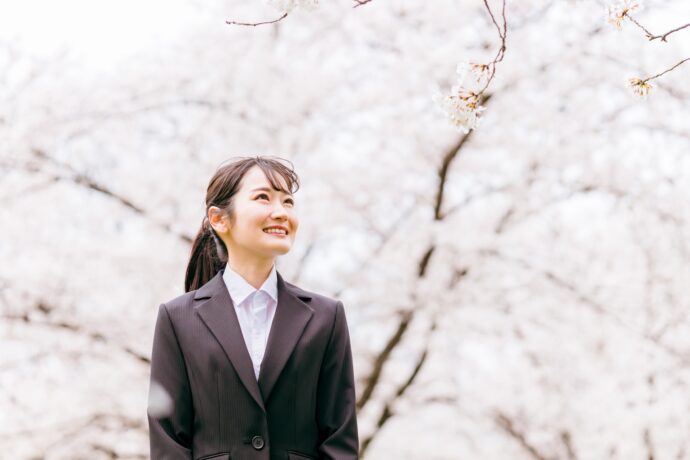 スーツの女性と満開の桜の風景