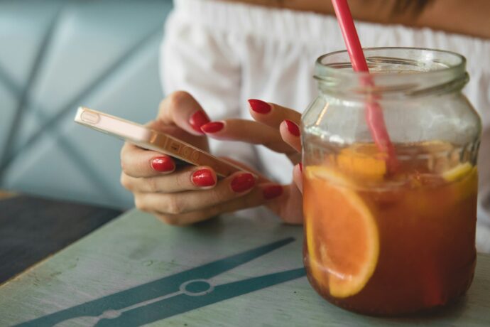 オレンジジュースを飲む赤ネイルの女性