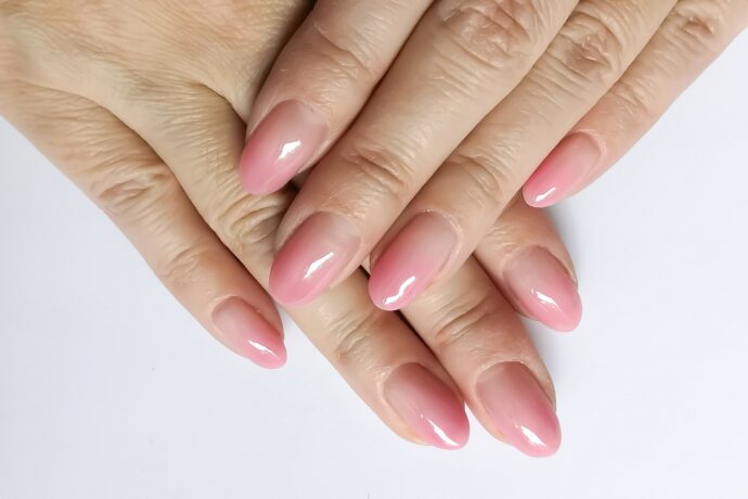 ピンクのジェルネイルをする女性の手